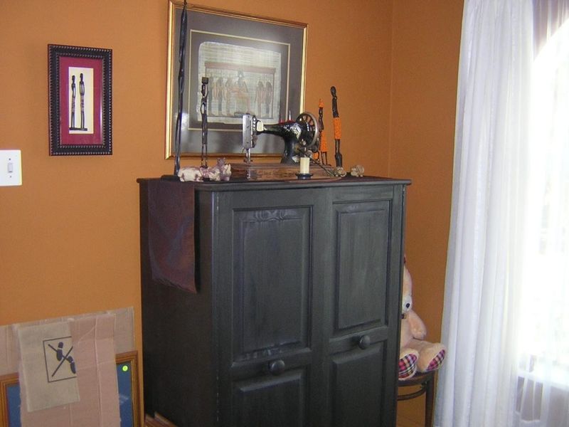 A bedroom interior featuring orange painted walls and a window with white curtains.