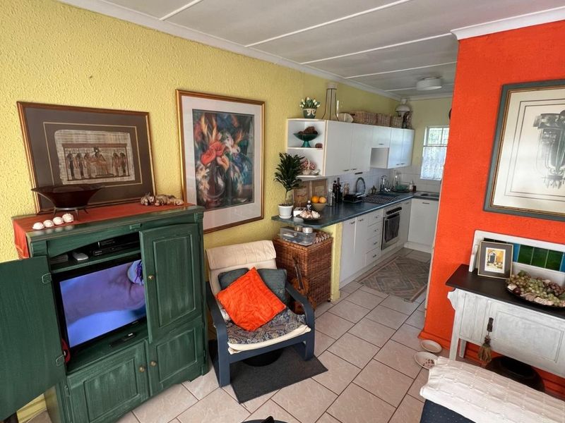 Open-plan living area featuring a functional kitchen with built-in cabinetry, oven, and hob, finished with tiled flooring throughout.