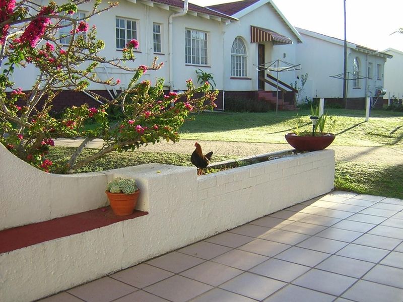 A rear exterior view of a townhouse featuring a tiled patio area with a low brick retaining wall and built-in bench seating.
