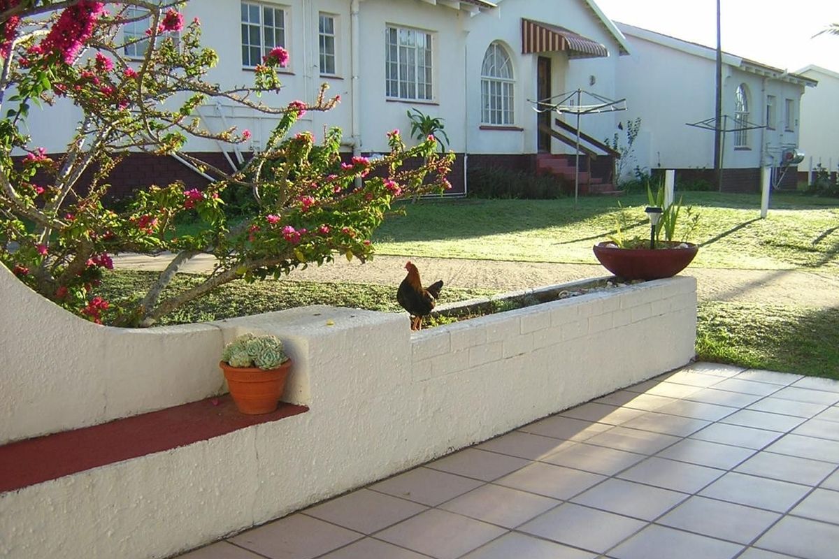 A rear exterior view of a townhouse featuring a tiled patio area with a low brick retaining wall and built-in bench seating.