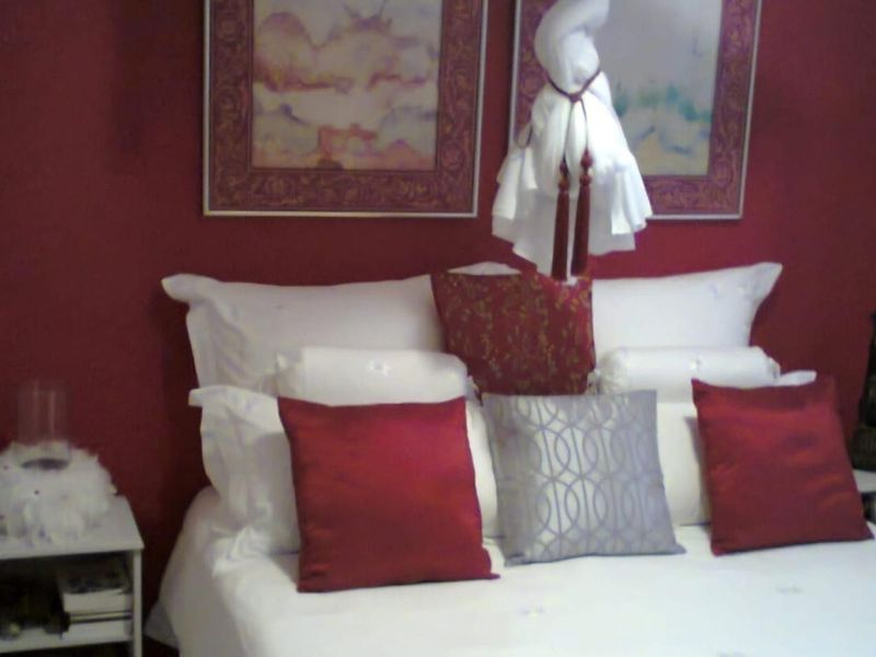 A bedroom featuring a deep red accent wall and neutral bedding, providing a cozy and intimate atmosphere for a primary or guest sleeping area.