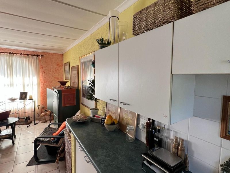 Open-plan kitchen and living area featuring tiled flooring, laminate countertops, and cabinetry, with potential for cosmetic updates to modernize the space.