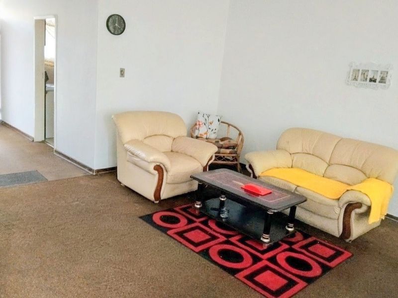 A living room area featuring wall-to-wall carpeting and access to an adjacent hallway.