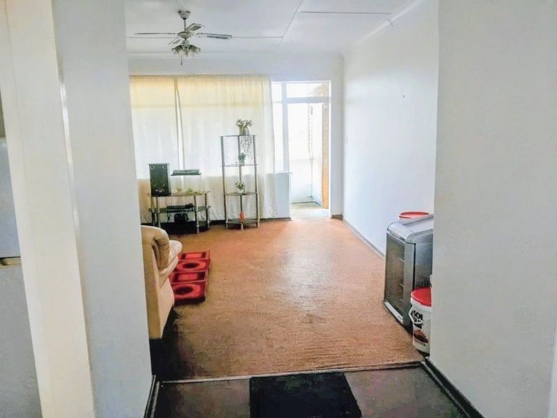 A living room area featuring a ceiling fan and access to an outdoor balcony through a sliding glass door.