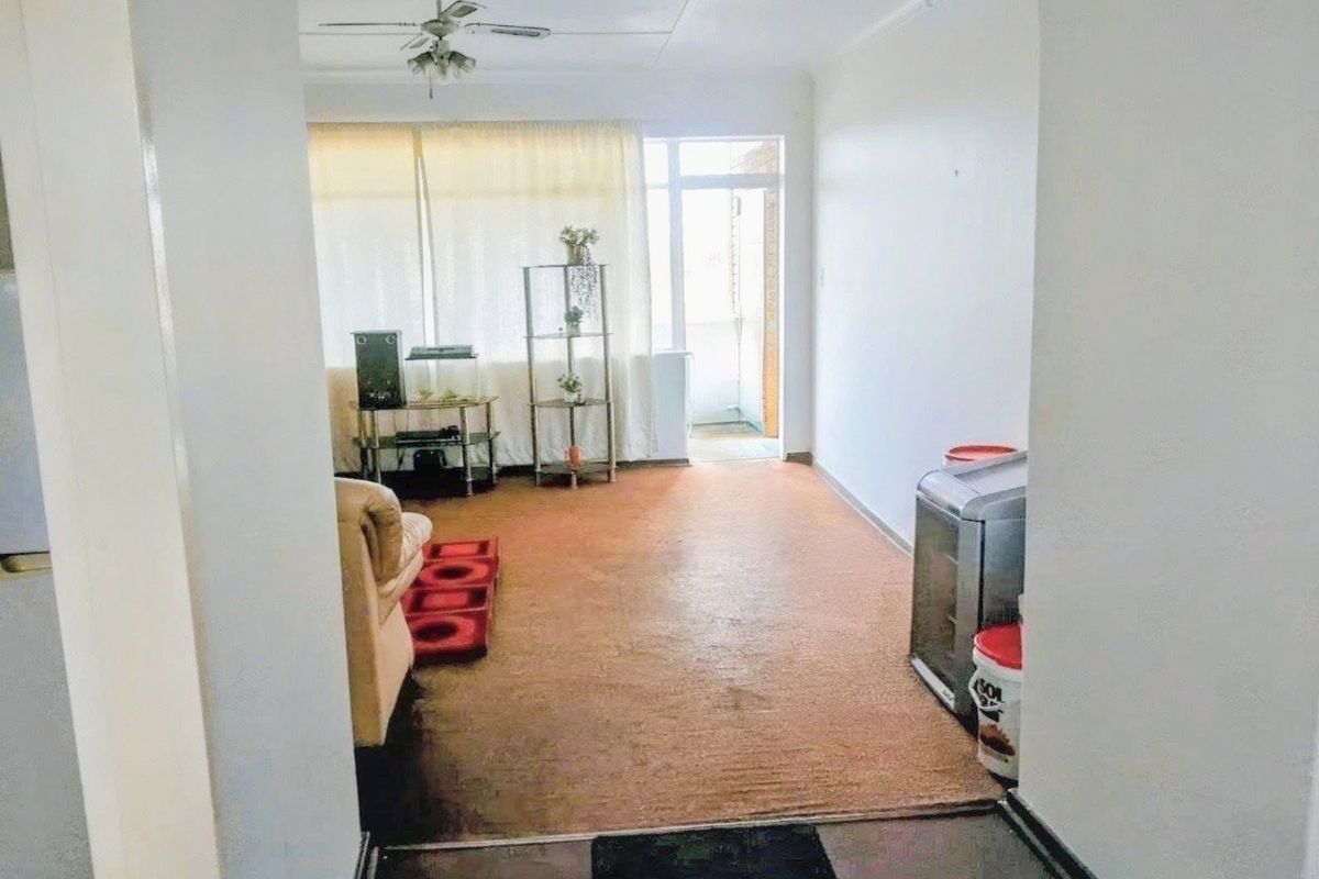 A living room area featuring a ceiling fan and access to an outdoor balcony through a sliding glass door.