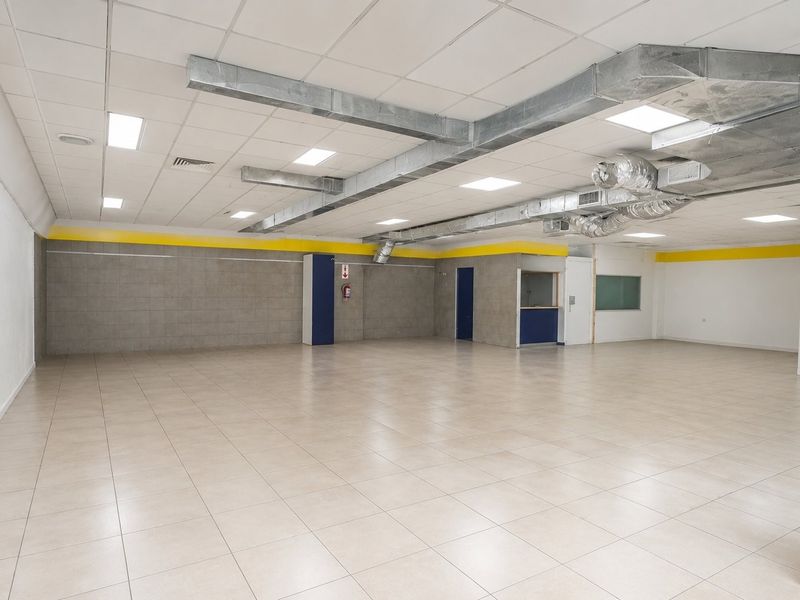 Spacious open-plan commercial area featuring tiled flooring, suspended ceilings with exposed HVAC ducting, and recessed lighting, suitable for retail or office use.
