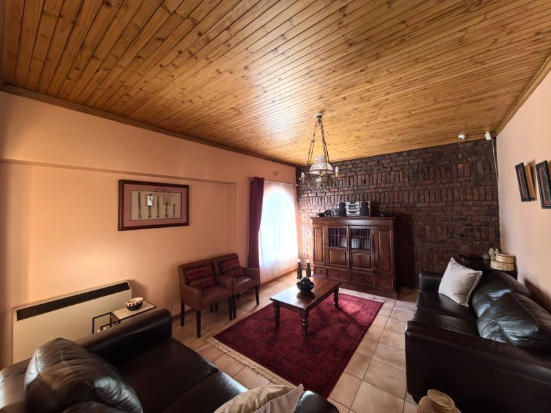 A cozy living room featuring a rustic exposed brick wall, warm timber ceiling, and tiled flooring, creating a traditional and inviting atmosphere.