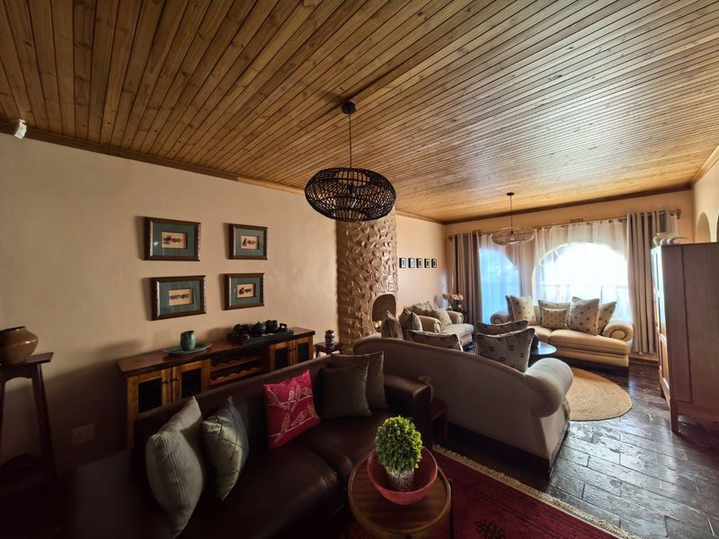 Spacious living room featuring a distinctive timber-clad ceiling, stone-clad fireplace, and large arched window, creating a warm and inviting atmosphere.