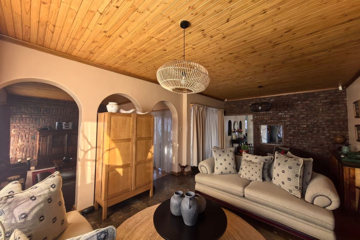 Spacious living room featuring a warm timber ceiling, exposed brick wall, and elegant arched doorways leading to adjacent living areas.