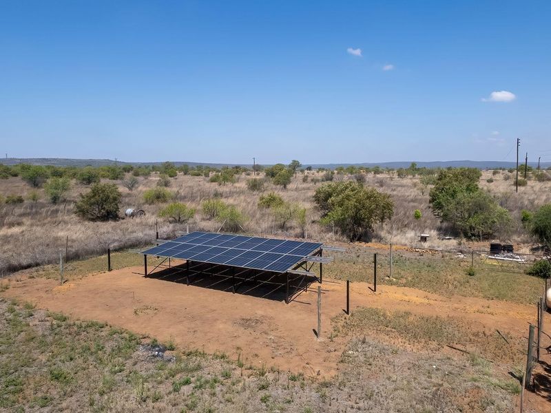 Aerial view of a ground-mounted solar panel array situated on a rural farm property.