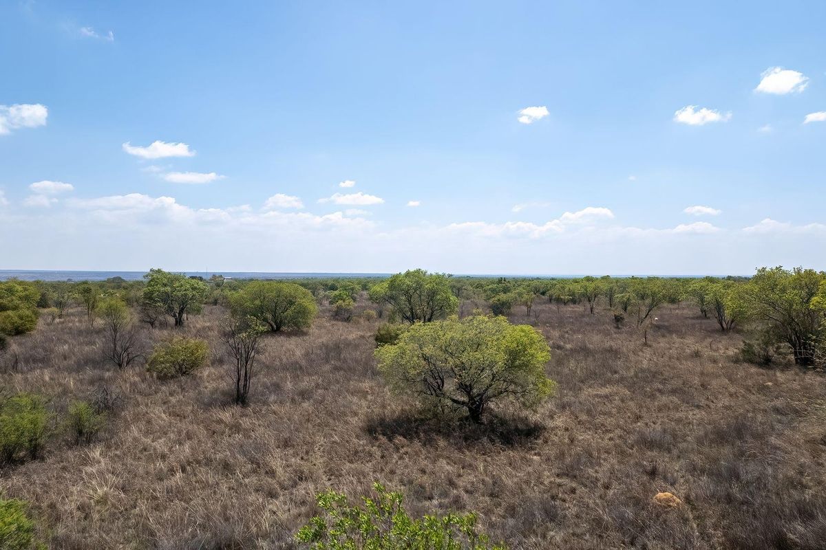 A wide-angle view of the expansive, natural landscape featuring native trees and dry grassland typical of the farm property.