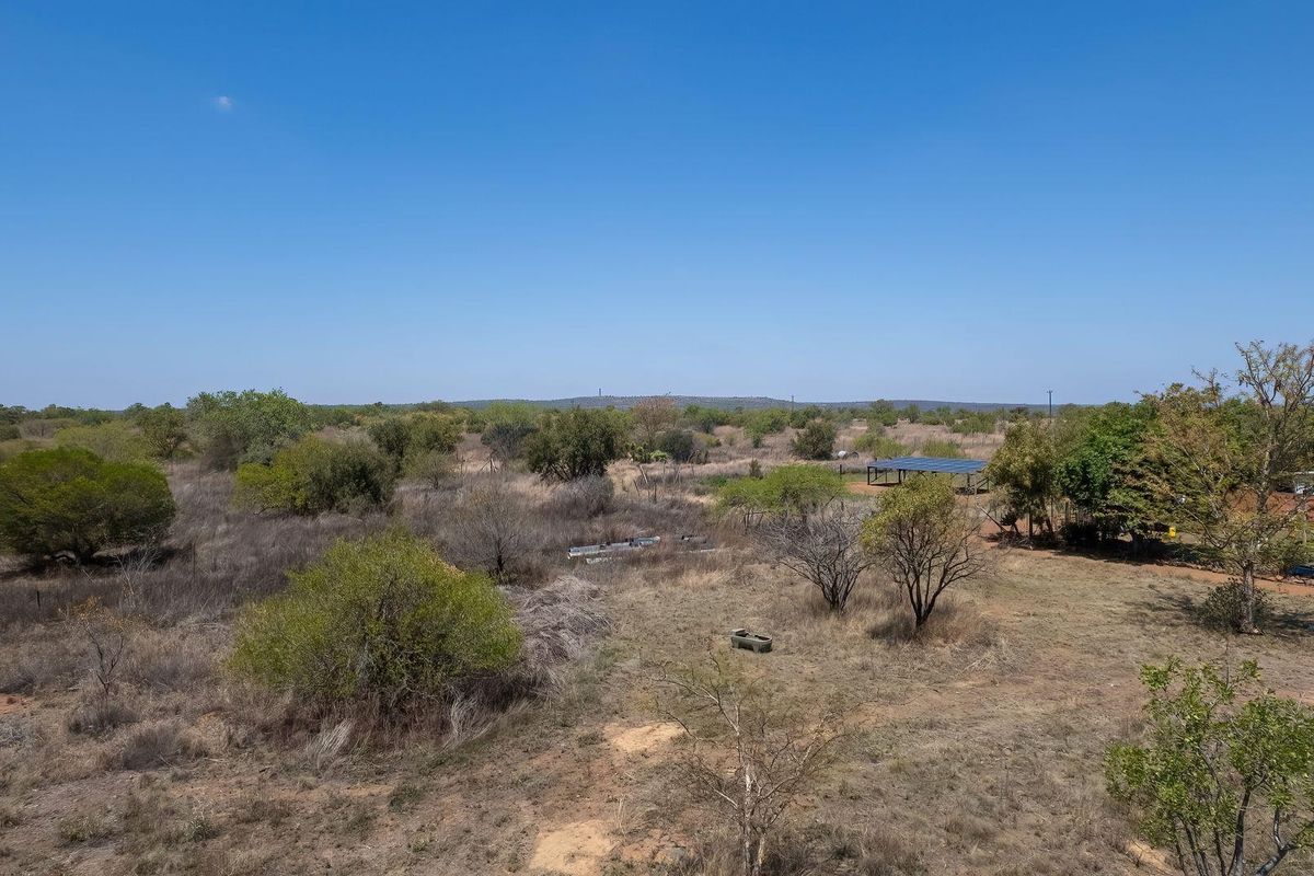 Aerial view of the expansive farm property featuring natural vegetation, open land, and a solar panel installation.