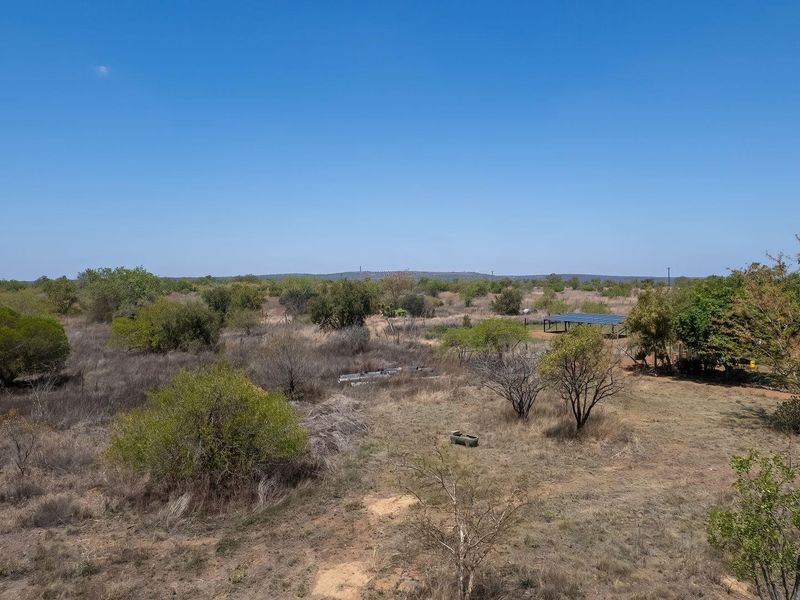Aerial view of the expansive farm property featuring natural vegetation, open land, and a solar panel installation.