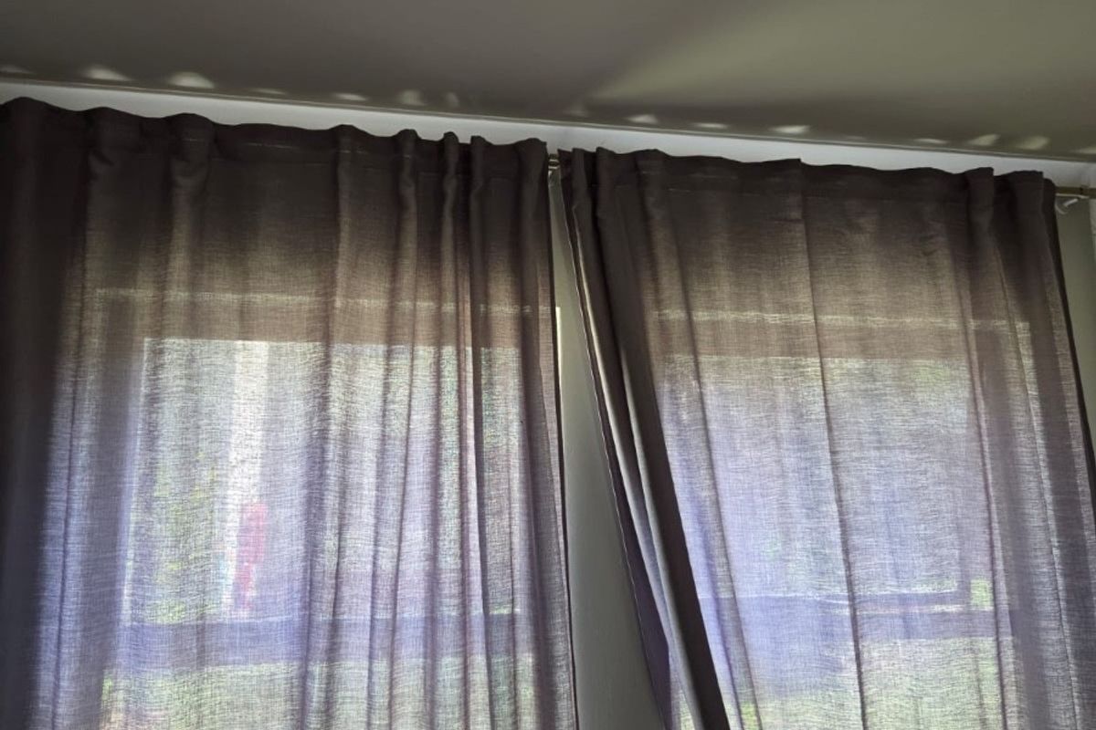 A view of a window with installed curtain rods and curtains, providing natural light into the room.