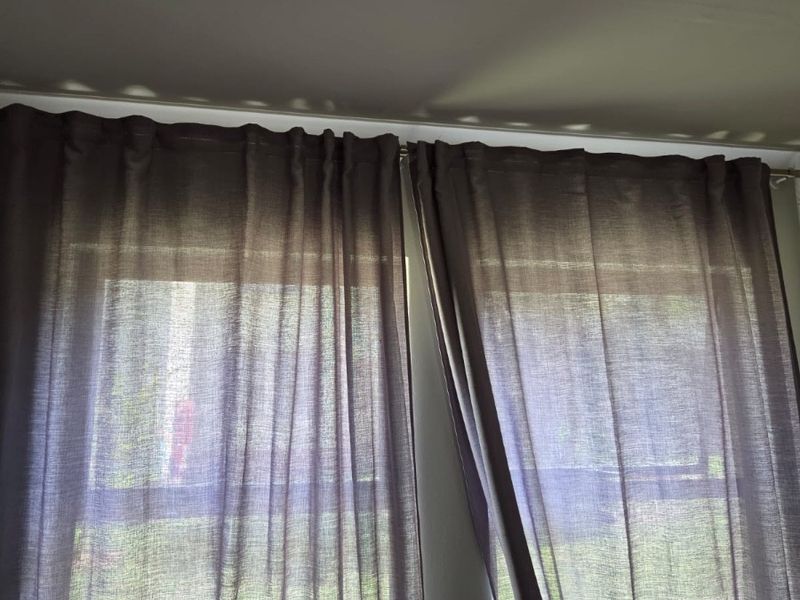 A view of a window with installed curtain rods and curtains, providing natural light into the room.