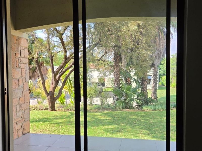 A view from inside looking out through a sliding glass door onto a covered patio with tiled flooring and stone feature wall.
