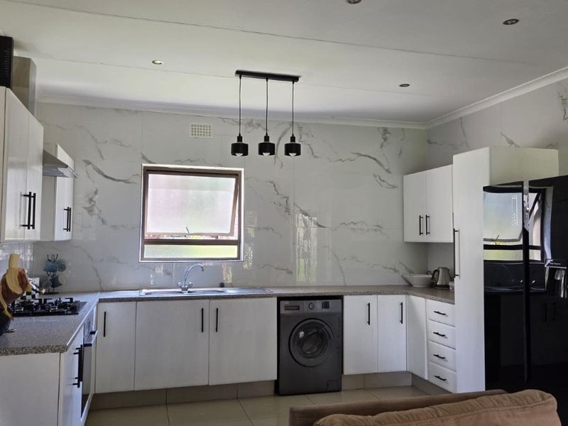 Modern open-plan kitchen featuring white cabinetry, marble-look splashbacks, gas hob, and integrated appliances, seamlessly connected to the living area.