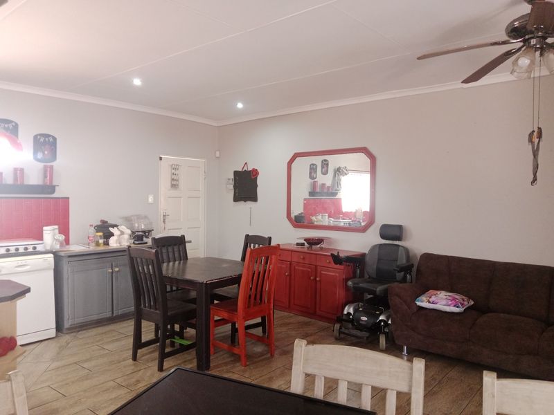 Open plan living and kitchen area featuring tiled flooring, recessed lighting, and a functional kitchen layout with red tiled splashback.