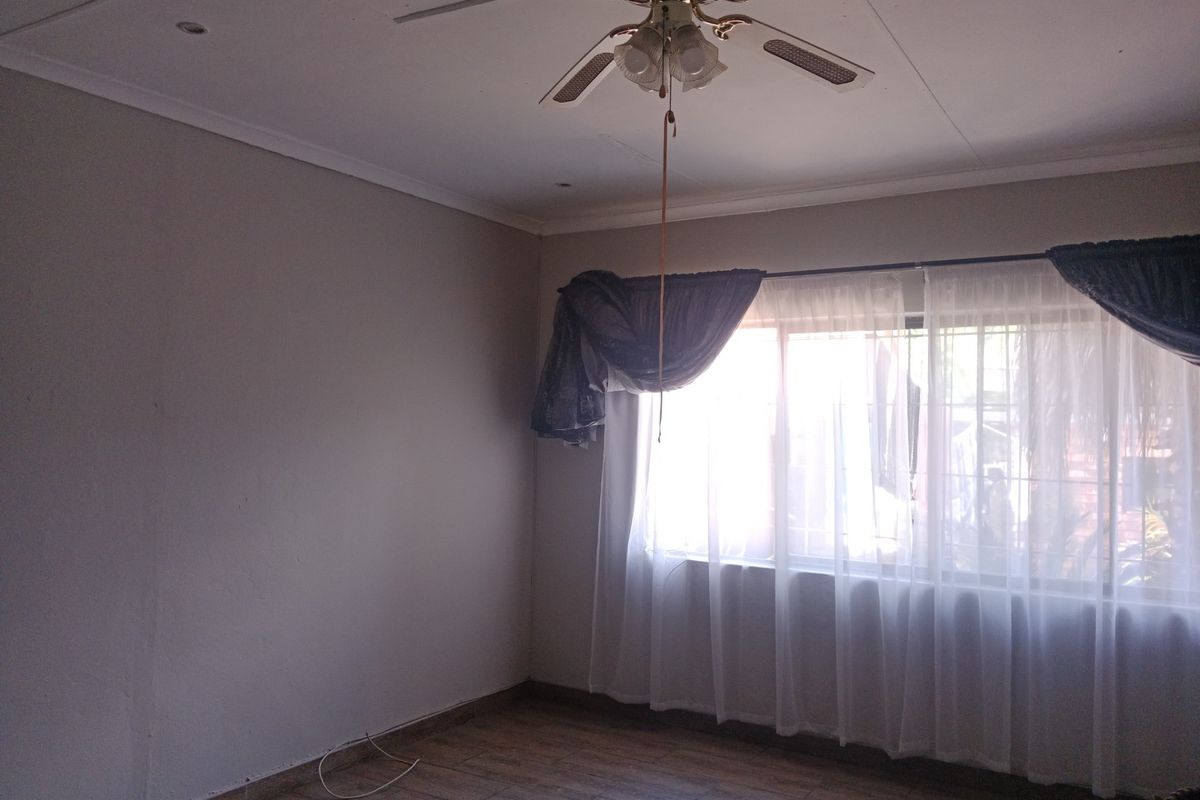 A vacant bedroom featuring tiled flooring, a ceiling fan, and window security bars, offering a neutral canvas for personalization.