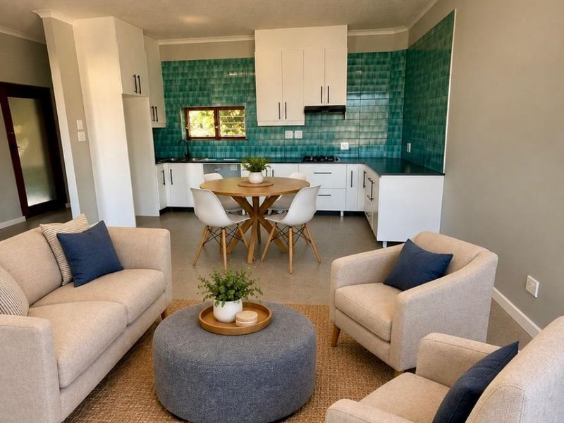 An open-plan living and kitchen area featuring modern white cabinetry, a vibrant green tiled backsplash, and neutral tiled flooring throughout.