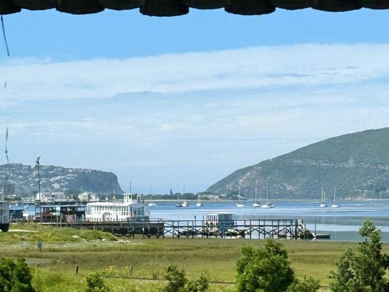 A scenic view overlooking the estuary, jetty, and surrounding hills, captured from an elevated position.