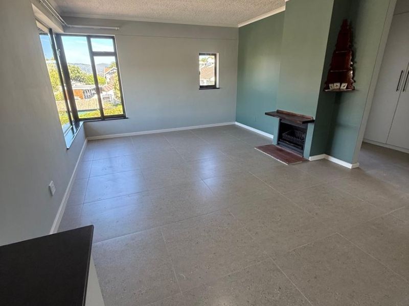 Spacious living area featuring neutral tiled flooring, a built-in fireplace, and large windows providing natural light and neighborhood views.