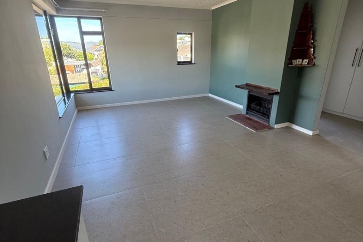 Spacious living area featuring neutral tiled flooring, a built-in fireplace, and large windows providing natural light and neighborhood views.