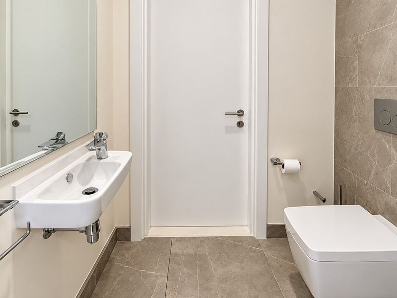Modern bathroom featuring a wall-mounted basin, wall-hung toilet with concealed cistern, and contemporary tiled finishes.