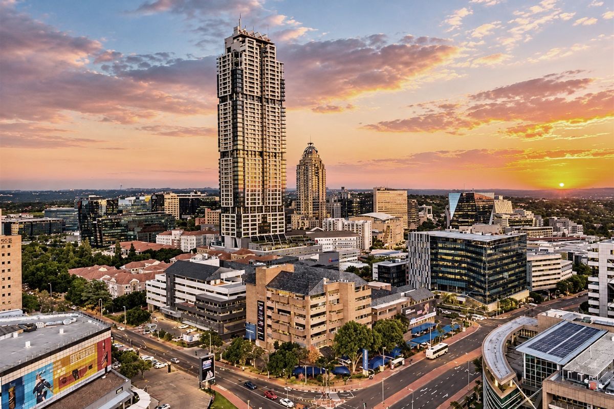 An expansive aerial view of the Sandton city skyline at sunset, showcasing high-rise commercial and residential architecture.