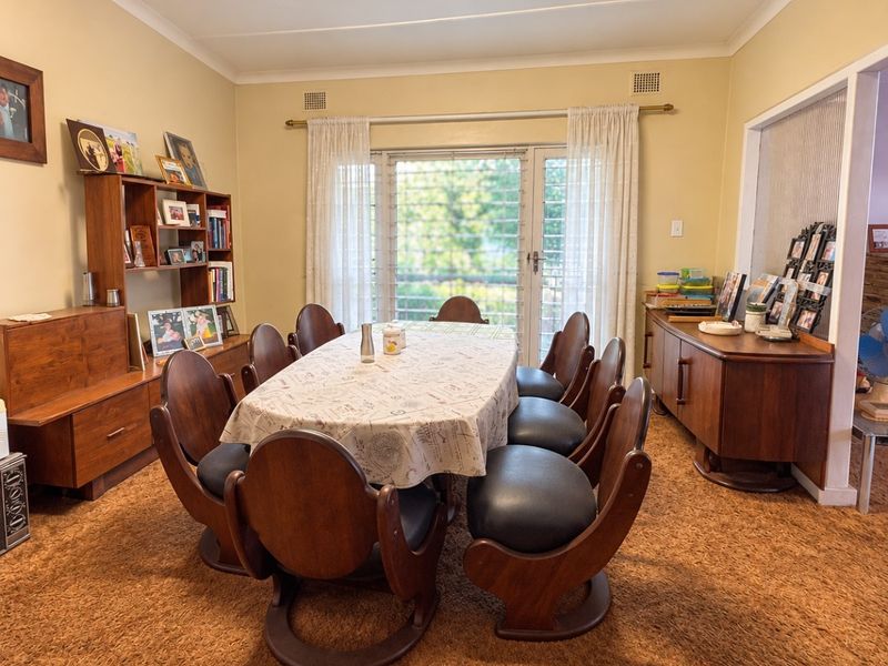A traditional dining room featuring carpet flooring, a central fluorescent light fixture, and a sliding glass door providing access to the exterior.