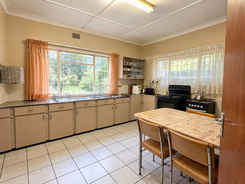 A functional, dated kitchen featuring original cabinetry, tiled flooring, and a double basin sink, offering significant potential for a modern renovation.