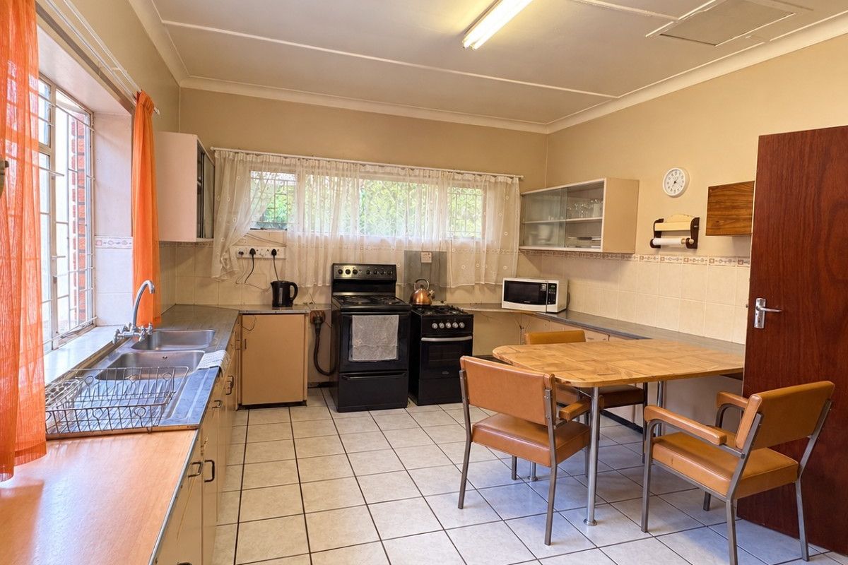 A functional kitchen featuring tiled flooring, built-in cabinetry, a double basin sink, and a freestanding stove, offering potential for modernization and cosmetic updates.