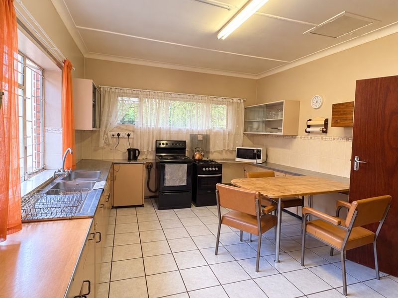 A functional kitchen featuring tiled flooring, built-in cabinetry, a double basin sink, and a freestanding stove, offering potential for modernization and cosmetic updates.