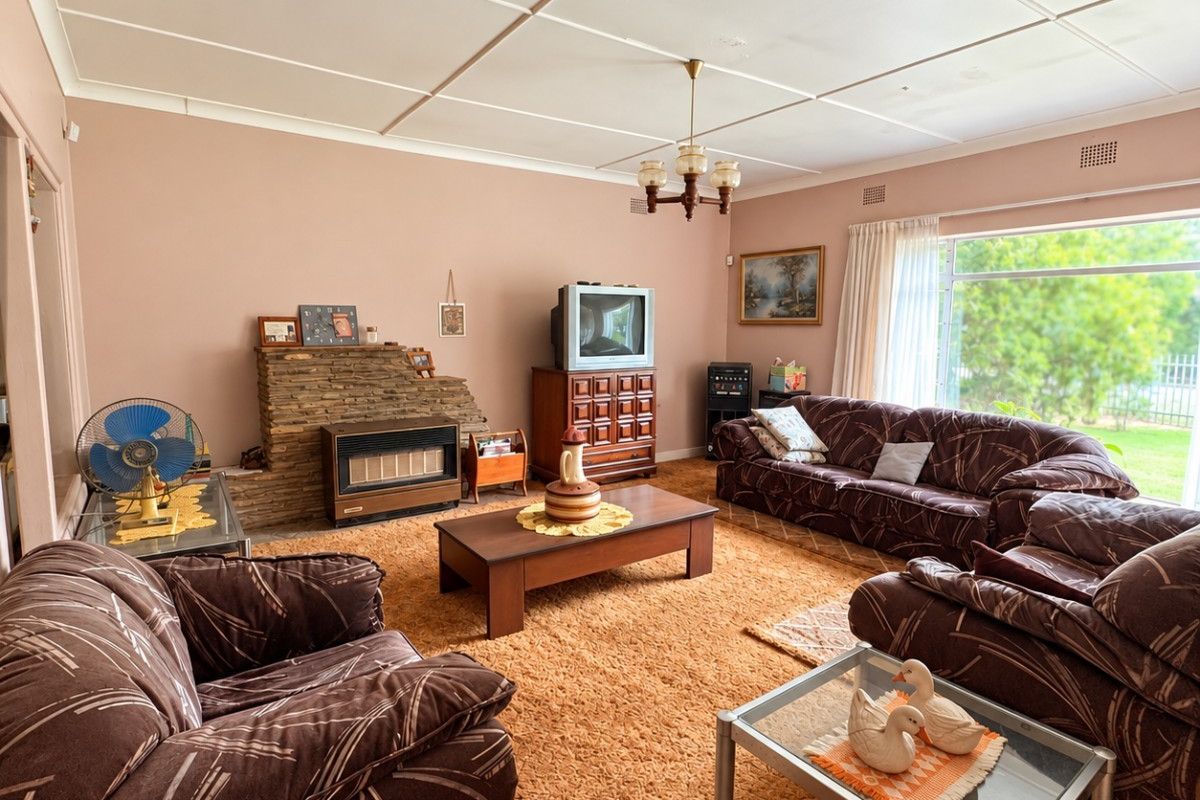 Spacious living room featuring a stone fireplace with a built-in gas heater, large window for natural light, and traditional ceiling tiles.