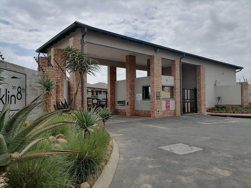 The secure entrance gatehouse of the apartment complex features brick pillars, a guard station, and controlled access gates.