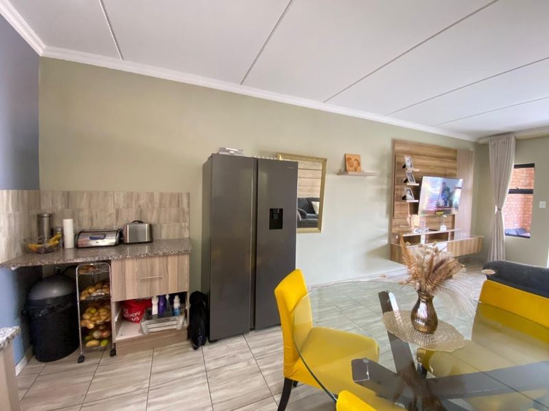 Open-plan living and kitchen area featuring tiled flooring, granite countertops, built-in cabinetry, and a wall-mounted media unit.