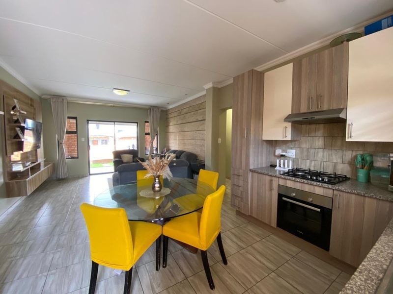 Modern open-plan living area featuring a well-appointed kitchen with built-in appliances, granite countertops, and seamless flow to the outdoor patio through sliding doors.