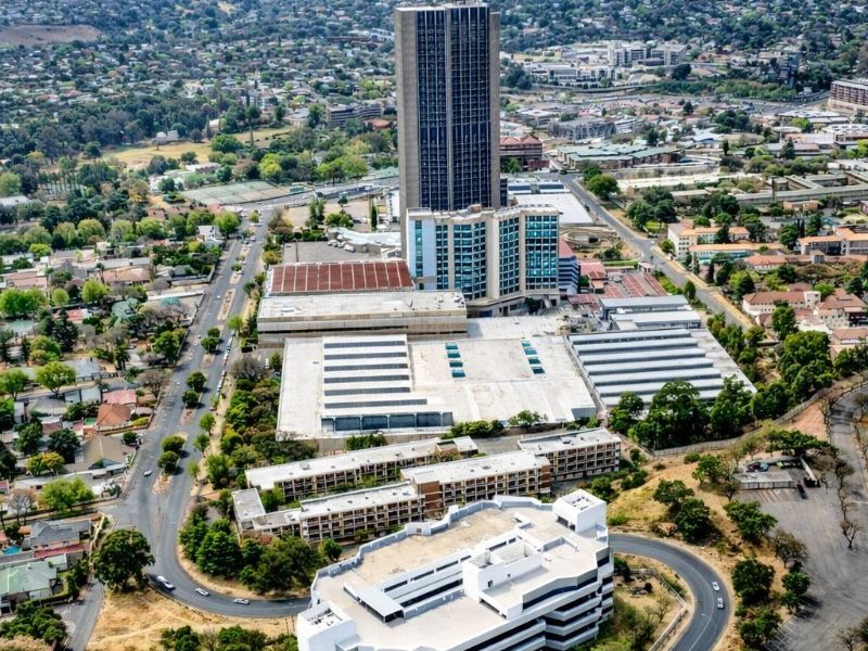Aerial view of a large commercial property complex featuring a high-rise tower, multi-level parking facility, and surrounding access roads.