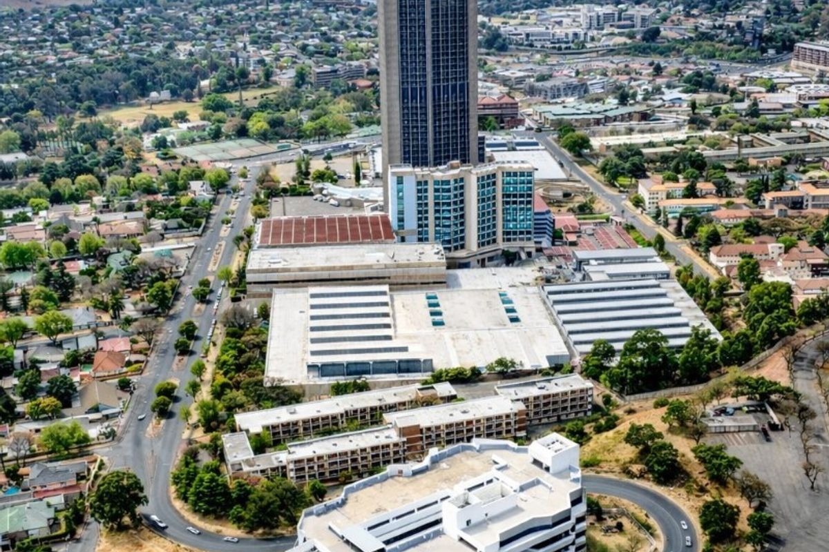 Aerial view of a large commercial property complex featuring a high-rise tower, multi-level parking facility, and surrounding access roads.
