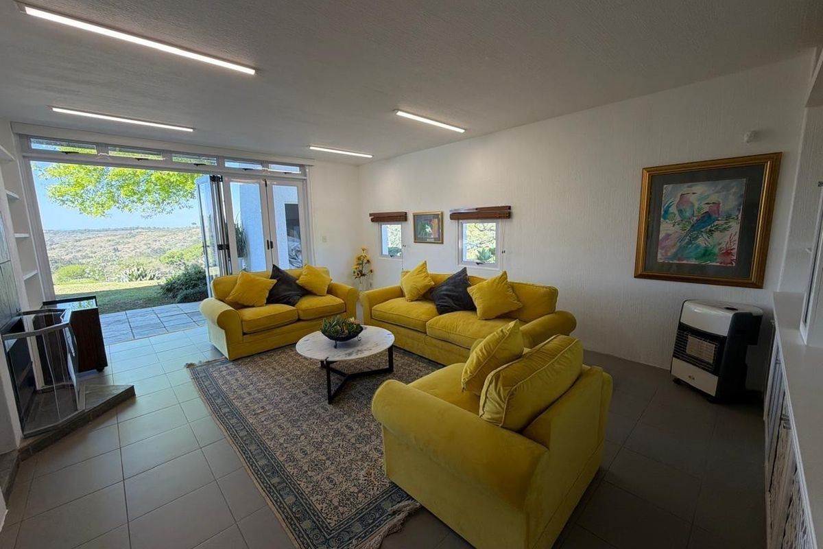 Spacious living room featuring tiled flooring, modern recessed lighting, and large bi-fold doors opening to a scenic outdoor view.