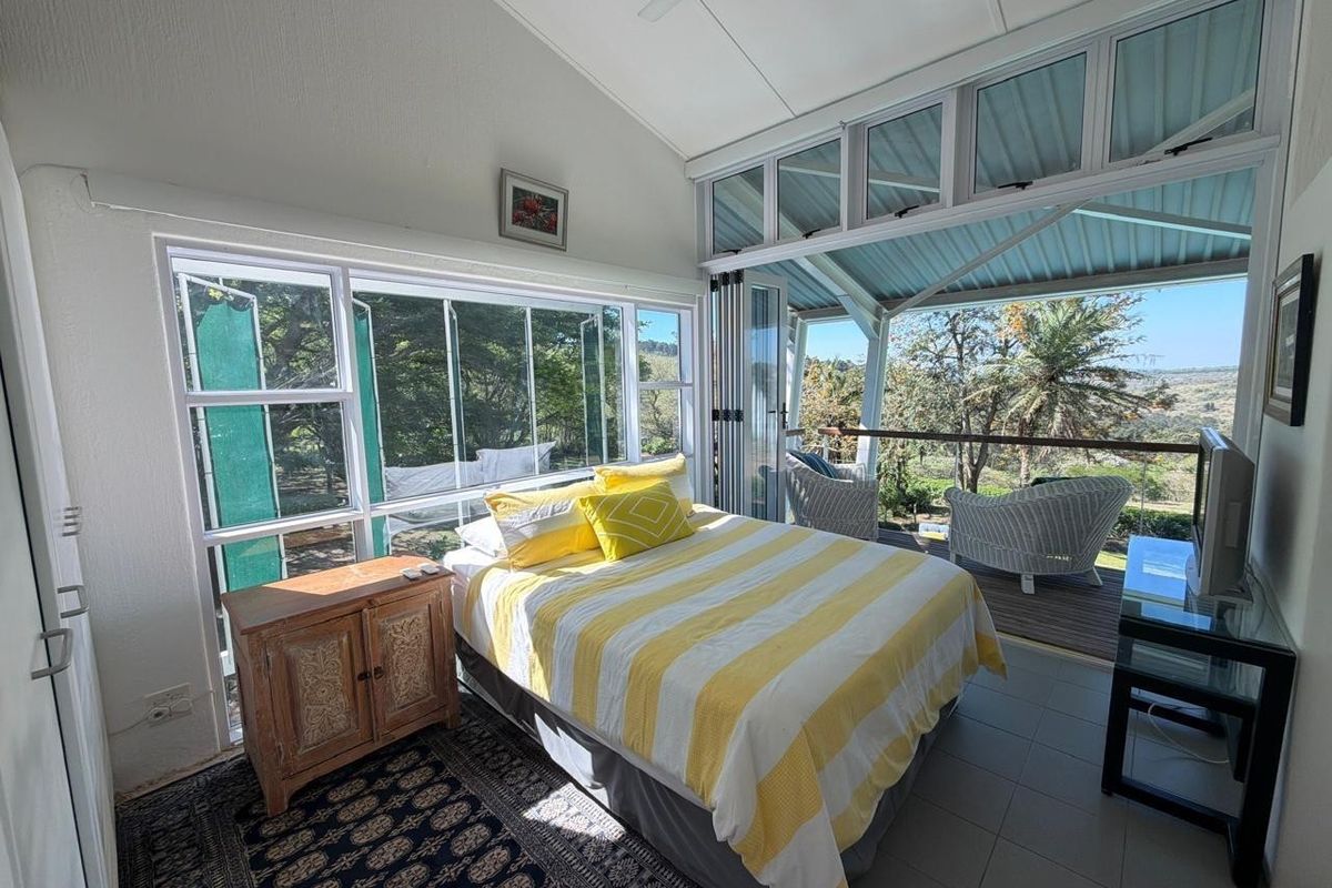 Bright bedroom featuring tiled floors, built-in storage, and expansive glass bi-fold doors opening onto a private balcony with scenic landscape views.