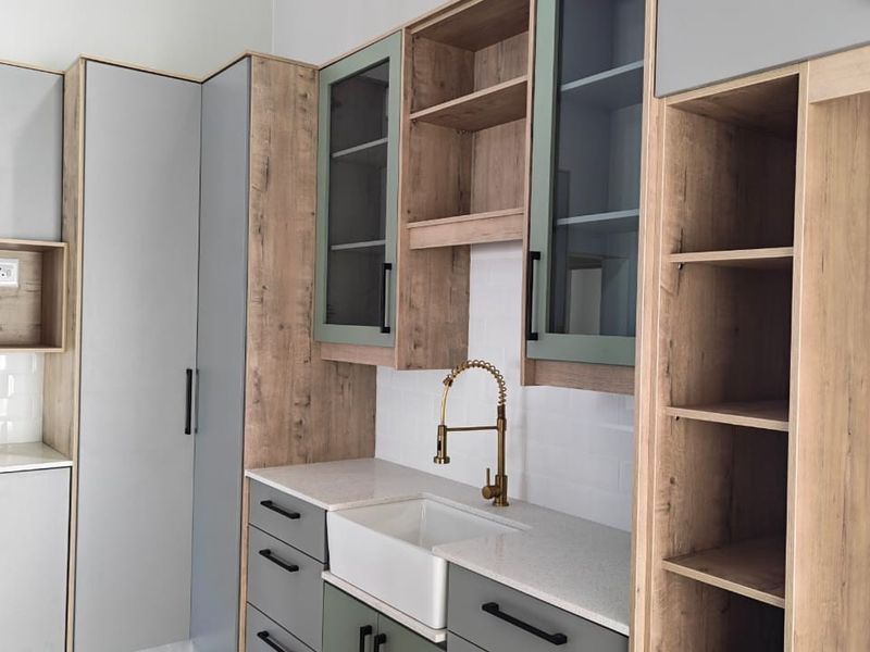 Modern kitchen featuring two-tone cabinetry, quartz countertops, a farmhouse sink with a brass gooseneck faucet, and a classic white subway tile backsplash.