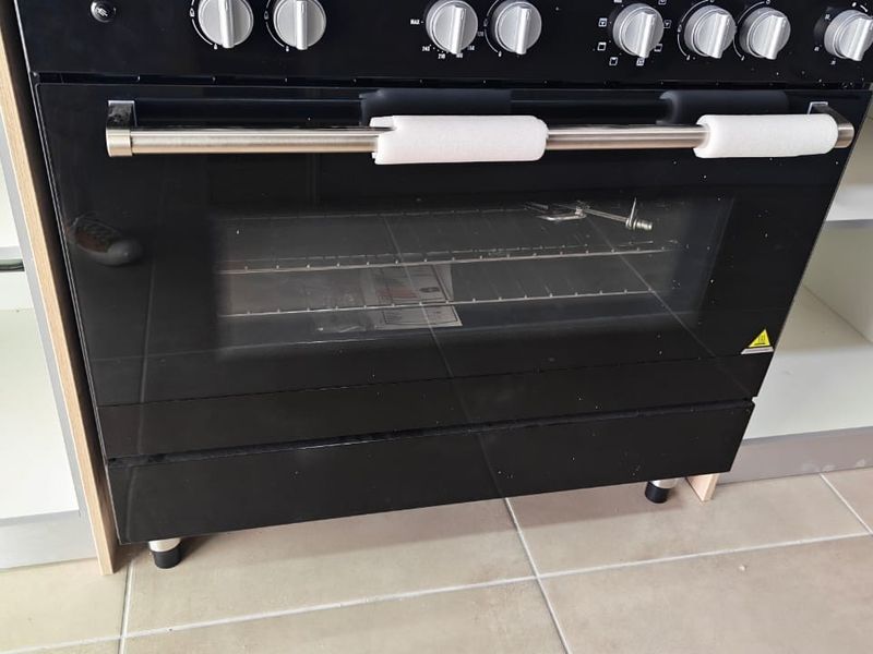 A close-up view of a modern black built-in oven installed within kitchen cabinetry, featuring clean ceramic floor tiles.