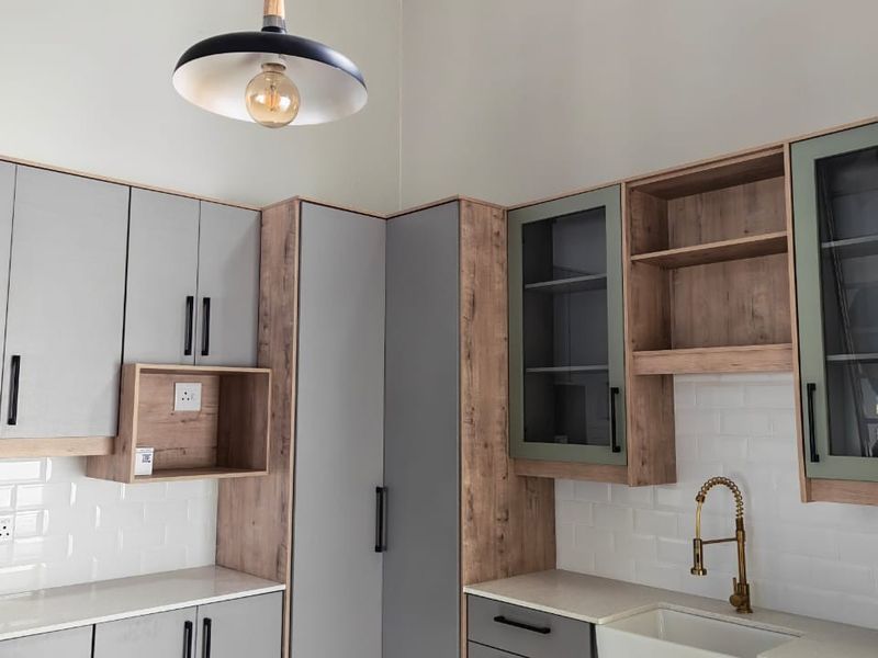Modern kitchen featuring two-tone cabinetry, subway tile backsplash, stone countertops, and a stylish brass faucet with integrated storage solutions.