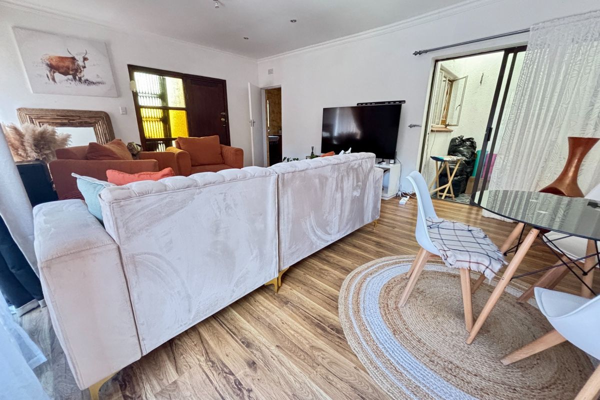 Open-plan living area featuring laminate flooring, recessed downlighting, and direct access to an outdoor space through sliding glass doors.