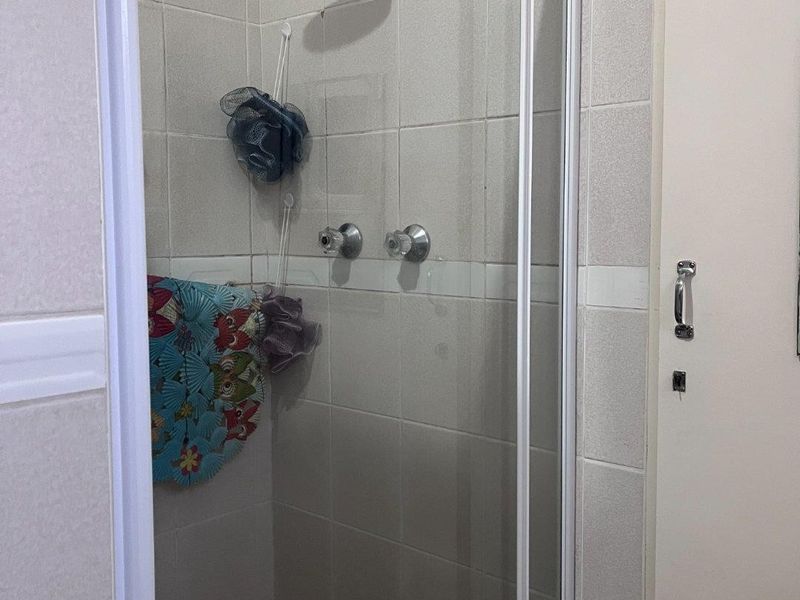 A functional shower stall featuring tiled walls, a modern shower head, and a glass enclosure.