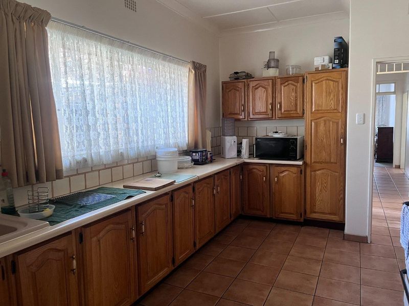 A functional kitchen featuring traditional wooden cabinetry, tiled backsplash, and durable floor tiles, offering a classic layout with ample storage space.
