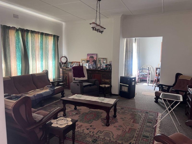A spacious living room featuring carpeted flooring and a central ceiling light fixture, offering a comfortable and functional living area.