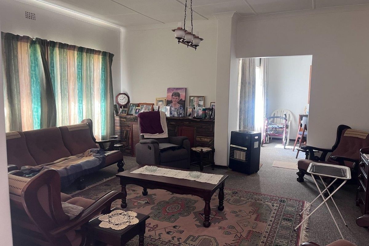 A spacious living room featuring carpeted flooring and a central ceiling light fixture, offering a comfortable and functional living area.
