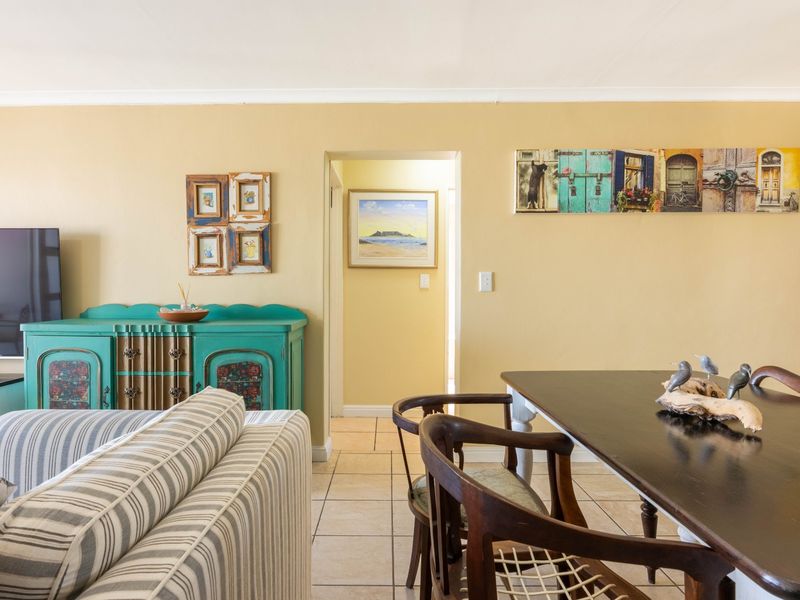 An open-plan living and dining area featuring neutral wall tones and tiled flooring, providing a functional space for relaxation and meals.